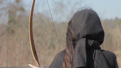 A girl shoots from a bow at targets.