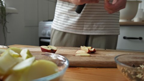 The chef girl cuts apples into pieces with a knife in the kitchen. The chef cuts apples on a wooden board. The process of creating a pie, the process of creating baking. Close-up. Slow motion