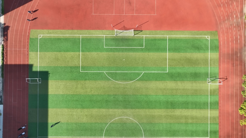 Drone aerial view of people running at the football stadium China. Group of people on the running track, the football field or soccer field. Sports, school and health concept b-roll footage
