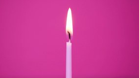 One cake candle burning on a pink background. Close up on burning pink or magenta cake candle. Full HD resolution slow motion happy birthday or anniversary video.