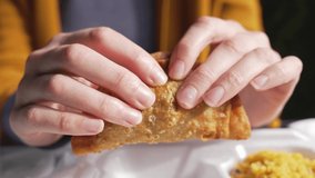 This video shows anonymous hands tearing a hot beef empanada in half, close up as it steams.