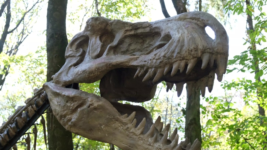 Dinosaur among the trees in the park. Robotic model at the exhibition