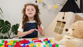 Cute girl kid vlogger sit at table recording vlog for social media blog with fluffy bear and toy colorful plastic construction blocks. Weekend leisure playtime activity, blogger, playthings store ad - Powered by Shutterstock - Get 15% off with code: PIKWIZARD15