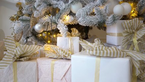 large number of beautifully packaged gifts under elegant Christmas tree with Christmas balls and garlands close-up. 4k resolution. New Year 2022. celebration Christmas miracle, surprise, Home comfort