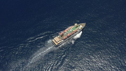 Aerial footage of ultra large container ship at sea or open ocean. A container ship carries cargo across the ocean. Cargo ship ploughs through waters at sea. Half loaded vessel moves at calm water.