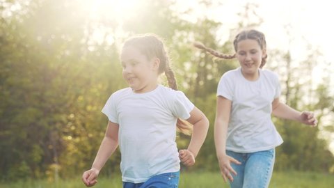 girls kid dream together run in the park at sunset. happy family people in fun the park concept. two sisters playing catch-up run. baby child running in green meadow. happy family kid dream concept