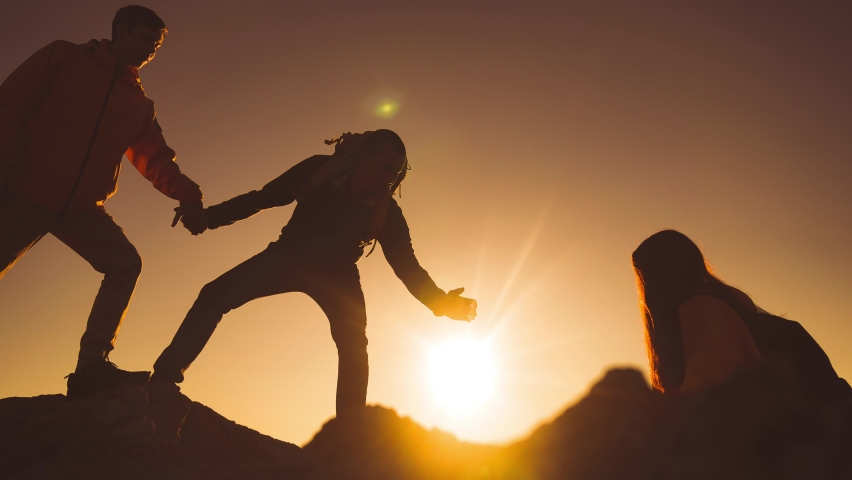 help team concept. team silhouette of climber stretching a helping hand to a friend. business teamwork success concept. silhouette business travel three sunlight tourists pull a helping hand Royalty-Free Stock Footage #1083056737