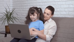 Chat with relatives on remote. A happy mother with her little nice daughter speak on remote with their relatives online on notebook.