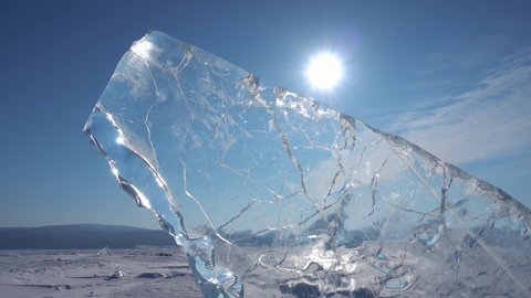 Sun shine through transparent hummock crystal clear frozen ice cracked iceberg Lake Baikal in winter. Russia abstract natural landscape cold season. Horizon. Frosty morning north Siberia. Dolly 4k