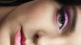 Closeup slow vertical motion video of human female face. Woman with natural face and eyes beauty pink makeup.