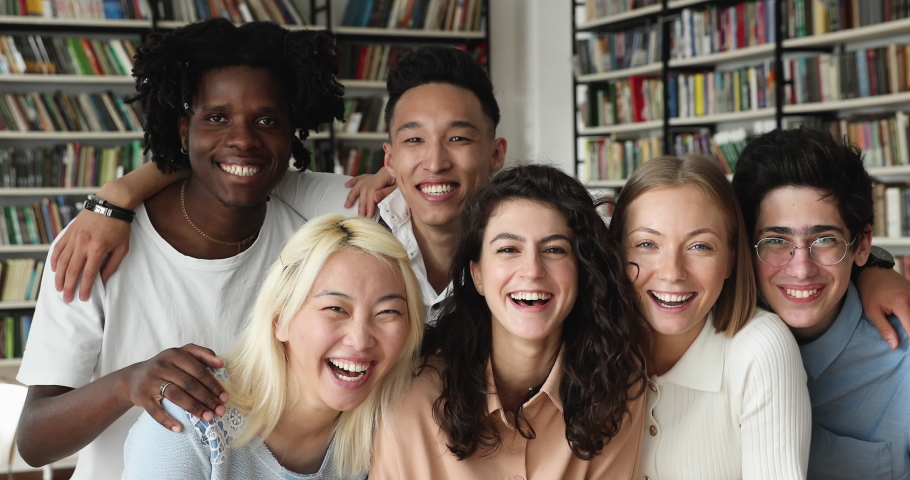 Group of young 17s happy multi ethnic college students smiling look at camera, posing in modern university library. Portrait of laughing friends different race and culture. Friendship, gen Z concept Royalty-Free Stock Footage #1083066172