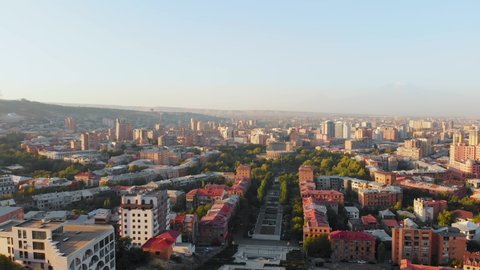 Aerial panning view city Yerevan panorama with Ararat mountain background; city architectural buildings, Tv tower . Mount Ararat, Armenia in clear day with hazy morning in city