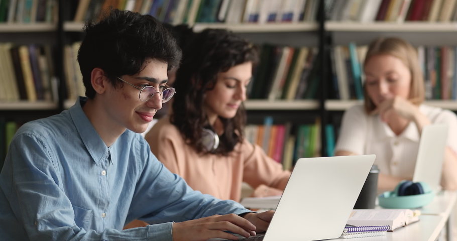 Student guy sit at table prepare for exam with laptop, writes essay, text coursework using computer sit at public or college library, makes research, do homework. Gen Z, modern tech, education concept Royalty-Free Stock Footage #1083072064