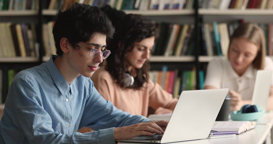 Student guy sit at table prepare for exam with laptop, writes essay, text coursework using computer sit at public or college library, makes research, do homework. Gen Z, modern tech, education concept | Shutterstock HD Video #1083072064