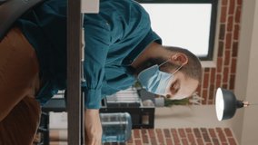 Employee looking at charts papers and laptop to work on business project and plan presentation. Man wearing face mask and working with data analysis on clipboard documents in office. - Powered by Shutterstock - Get 15% off with code: PIKWIZARD15