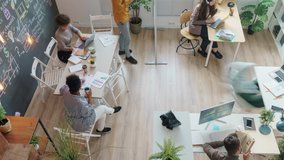 Zoom-in high angle view of diverse creative team working in shared office talking cooperating using laptops writing on chalkboard wall - Powered by Shutterstock - Get 15% off with code: PIKWIZARD15