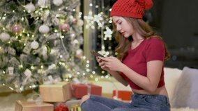 Portrait of beautiful Asian girl sit on floor making facetime video calling with smartphone,use mobile meeting online app,recording stories for social media on Christmas Eve in room at night at home. 