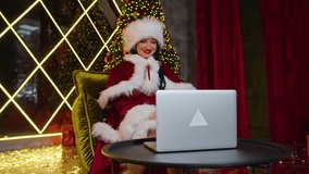 happy woman Mrs. Santa communicates on laptop in her christmas office. holidays in quarantine. remote communication, holiday gifts and discounts.