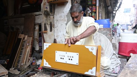Lahore, Pakistan, 25 ‎November ‎2021. A worker working on new harmonium keys.