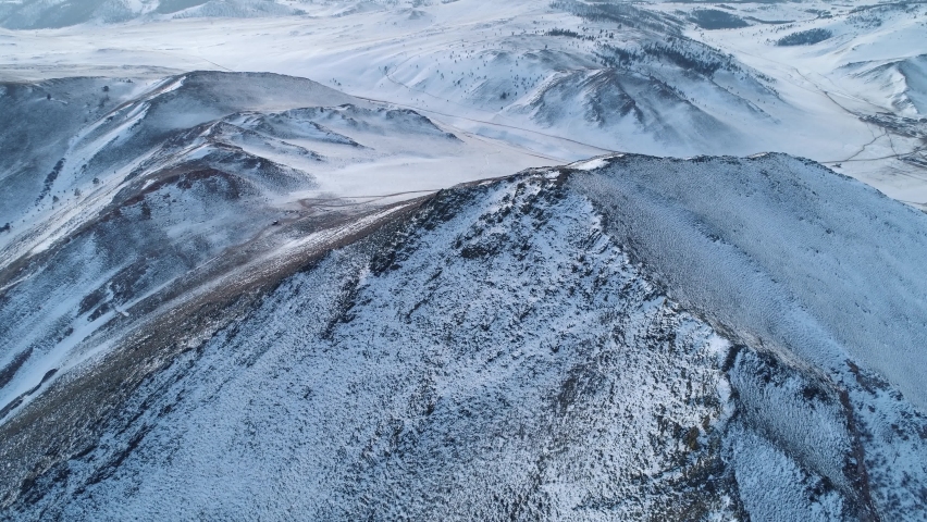 Aerial forward Epic winter snow-covered mountain tundra Buryatia, Siberia abstract natural landscape. Roads through wild untouched terrain, off-road. Hills shaman's way. Reserve. Open space, horizon
