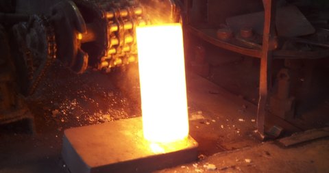 The incandescent metal moves along the conveyor belt. Metal blanks. Production of heavy industry and large-sized metal structures. Modern steel industry.