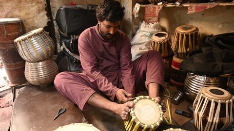 Lahore, Pakistan, 25 ‎November ‎2021. Pakistani tabla maker tightening and tuning the surface.