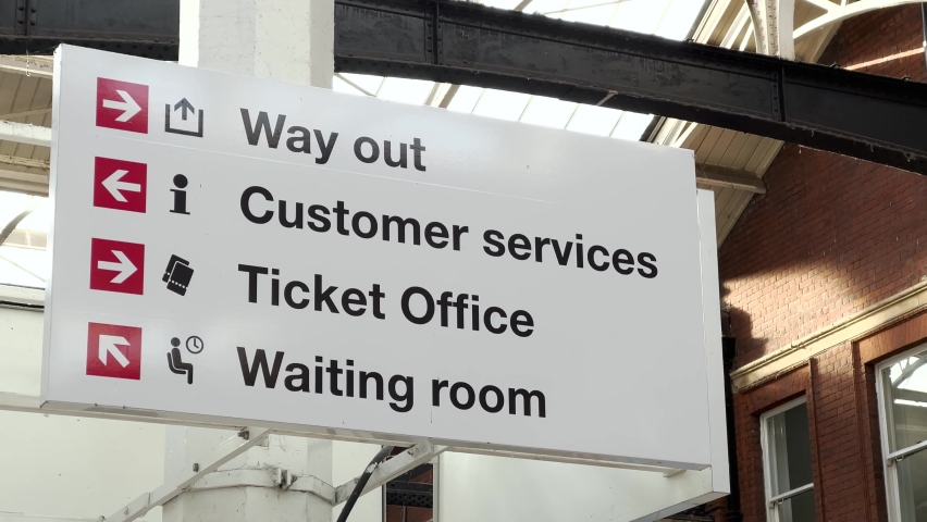 Large overhead signage at a British railway terminus, indicating the location of the ticket office and waiting room.