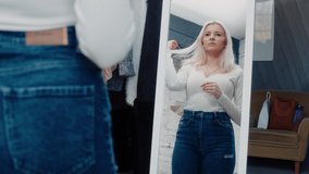 Isolated Beautiful Caucasian Influencer Model Standing In Front of the Mirror Looking at Herself, Fixing Her Hair and Clothes, Getting Ready to Film a Vlog for Her Social Media Account.