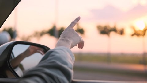 free girl hand out of the window rides a car wind in the face. concept car travel on the road. girl stretches her hand out of the car window sun glare sunset. happy and freedom car insurance concept	