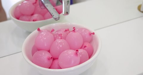 a bunch of pink water balloons in a sink. ready for the kid's water fight. leisure activity