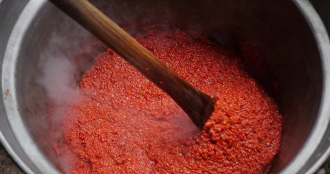 Cooking a large amount of ajvar. Balkan national dish. Preparing food for the winter. Gastronomy tradition and winter holidays. Stirring food.