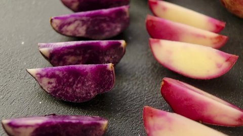 colored potatoes cut into wedges before baking on a dark background close-up selective focus.