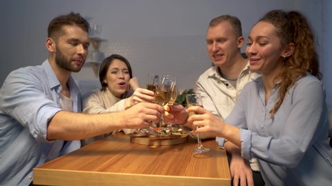 A group of people toasting and drinking champagne at home. Glasses with sparkling champagne. The guys congratulate and communicate using a video call. New normal lifestyle, social distancing concept