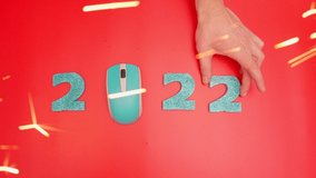 the numbers 2022 on red background with computer mouse. Sparklers are lit on sides. 4k video congratulations on new year of office workers. Computer store, flatlay video. it technologies, Innovations