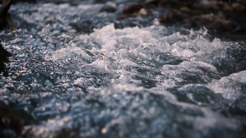 Slow motion of wild clear mountain river , stream flowing through rocks. Close up of river stones with flowing water, clean water flowing in a mountain river