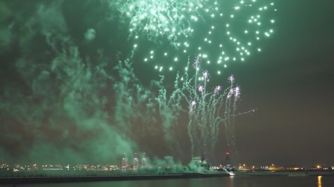 New Year firework display on Liverpool waterfront at night. Tilt down shot against dark city skyline.