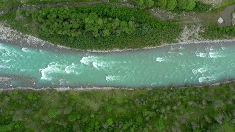 Top Down view of Fast Moving Mountain River with Rapids. Aerial View of Natural Winding River in Green grass field