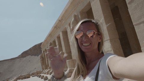 Young woman sightseeing ancient Egyptian temple in Luxor takes cool selfie
