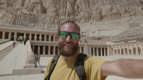 Young man sightseeing ancient Egyptian temple in Luxor takes cool selfie