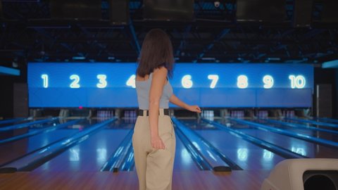 A Hispanic woman jumps joyfully looking into the camera, celebrate the victory in slow motion. Throw in the bowling alley to make a shoot. Victory dance and jump with happiness.