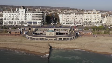 Eastbourne Bandstand on the Seafront of Grand Parade with Devonshire Place leading away behind the Bandstand. Aerial video.