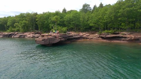 People cliff jumping from a rock into Lake Superior on a summer day, having fun at Madeline island Apostle island Lake Superior Wisconsin, travel and enjoy the outdoors