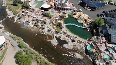 Aerial flyover hot springs resort in pagosa springs during bright sunny day in Colorado City. Tranquil river beside water park