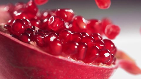 Pomegranate Grains rolls down on surface of broken pomegranate in slow motion