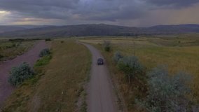 4k aerial footage of a car chase on dirt road at the sunset.