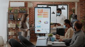 Diverse coworkers meeting to plan business growth and project during coronavirus pandemic. People working together to design marketing strategy and data analysis for financial presentation. - Powered by Shutterstock - Get 15% off with code: PIKWIZARD15