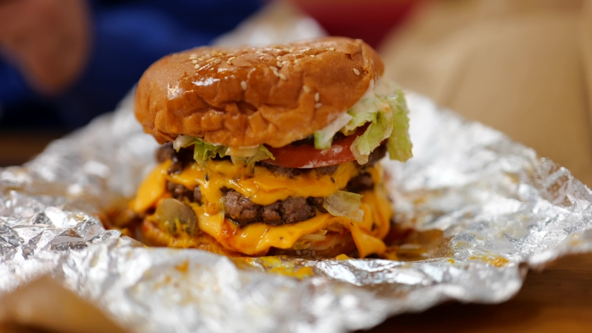 Big juicy triple patty beef burger with cheese, lettuce and tomato