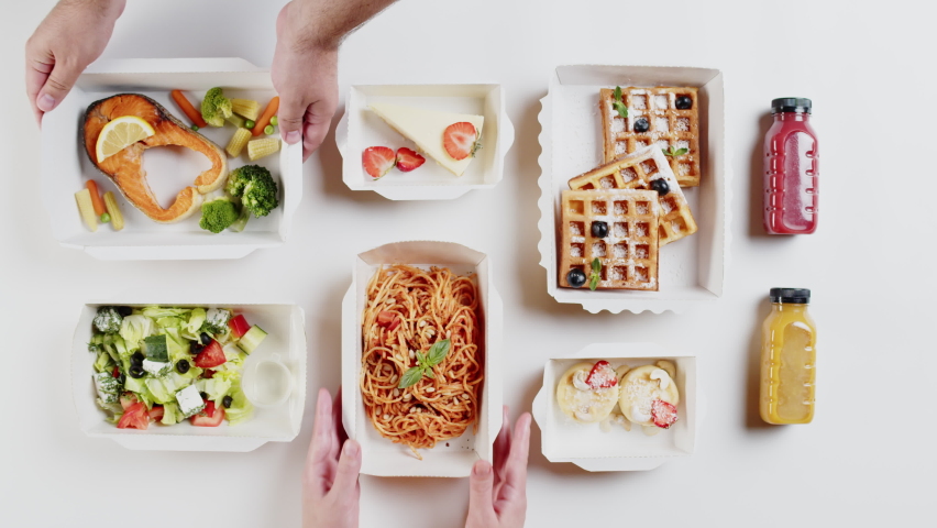 Food delivery top view, take away meals in disposable containers on white background. Putting lunch boxes with fried fish and spaghetti bolognese. Healthy diet. Catering service concept.
