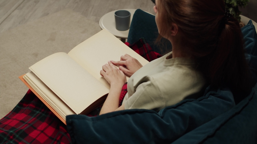 Blind woman reading braille book top view, poorly seeing female person learning to read, home education for people with disabilities, touching letters on sheet of paper.