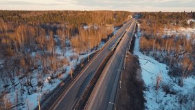 Fabulous winter landscape with a motor road at sunset, aerial view. The ground is covered with white snow. Video, footage, splash screen, intro, presentation, copy space. UHD 4K.